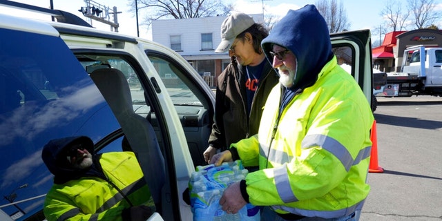 Volunteer Larry Culler helps load water into a car in East Palestine, Ohio, as cleanup from the Feb. 3 Norfolk Southern train derailment continues, Friday, Feb. 24, 2023.